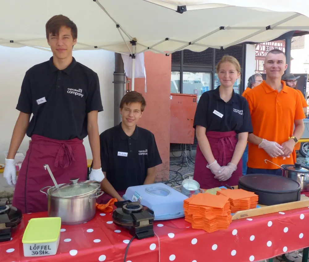 Jugendliche an einem Kochstand mit Waffeleisen und Kochtopf beim Tafel-Jubiläum